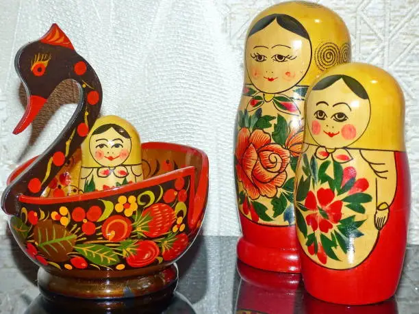 Semenovskaya matryoshka and bright Khokhloma bird - traditional Russian folk art. Matryoshka-Russian folding doll made of wood, inside which there are dolls of smaller size. Souvenirs