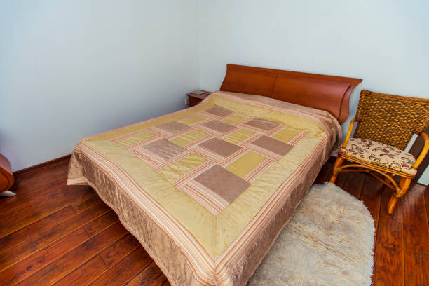 istock A large bedroom with a mahogany bed, wicker chairs, and an elegant dressing table with a semi-circular mirror. The bed has a beige blanket in squares. mahogany parquet 1210696156