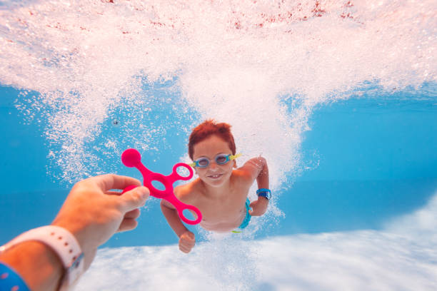 istock Child swim dive underwater take toy from teacher 1210697801