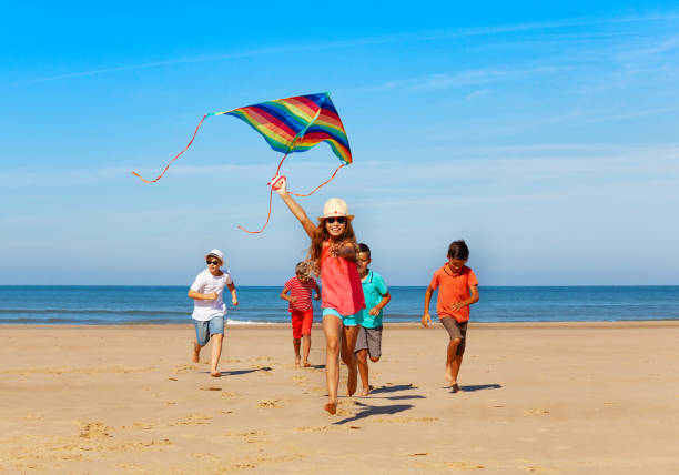 group of happy kids run with kite on the beach - stripped shirt imagens e fotografias de stock