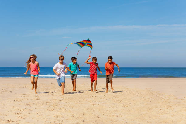 istock Group of kid run with colorful kite on a beach 1210697814