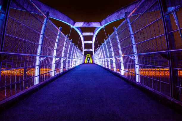 Bright white LEDs illuminate pedestrian walkway over highway at night