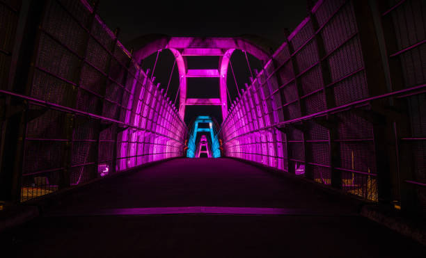 istock Bright purple leds illuminate pedestrian walkway over highway at night 1210704794