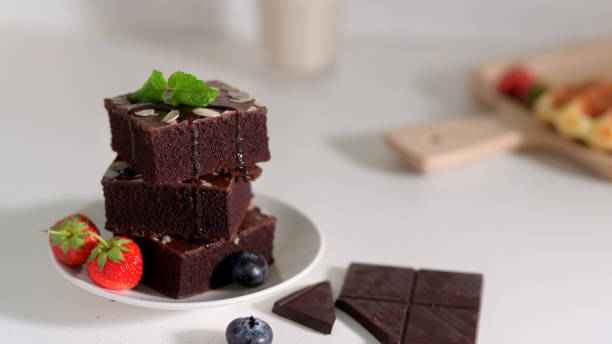 istock Close up view of stack chocolate brownies on white plate with mint leaf on top 1210707795