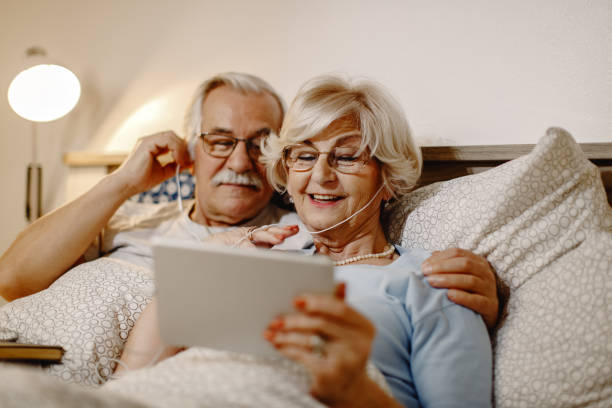 istock Happy senior couple surfing the net on touchpad while resting in bedroom. 1210708938