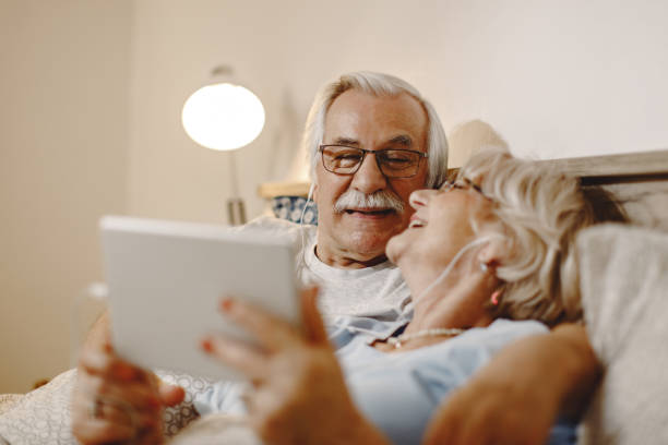 istock Happy mature couple having fun while using touchpad in bedroom. 1210708939