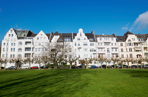 Duesseldorf, Germany- March, 03. 2020: Classic townhouses (partial art nouveau) at the promenade beside the river Rhine at Duesseldorf-Oberkassel, a lawn in the forground.
