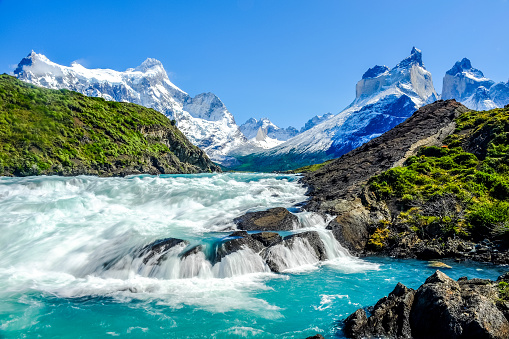 Beautiful Patagonia landscape photo at Salto Grande Waterfall with the Andes mountain range in the background at Torres del Paine National Park, Chile.