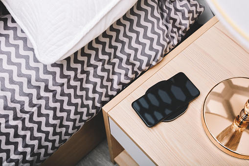 The mobile phone in the bedside wireless charging is in the bedroom，Science and technology life concept