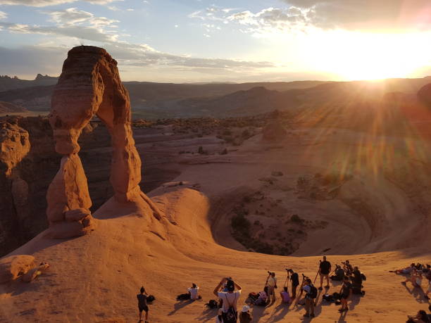 Delicate Arch sunset in Arches nationalpark Utah USA Sunset at delicate arch viewpoint in Arches nationalpark in Utah USA with crowd of photographers and tourists taking photos of red sandstone arch formation in evening light / sunlight delicate arch stock pictures, royalty-free photos & images