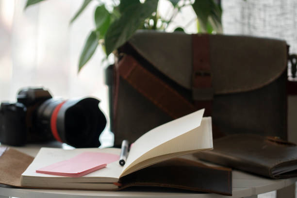 istock camera, suitcase and notebook on table in front of window 1210714347