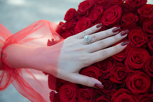 Red roses bouquet with engagement ring. Bride with flower bouquet and engagement ring