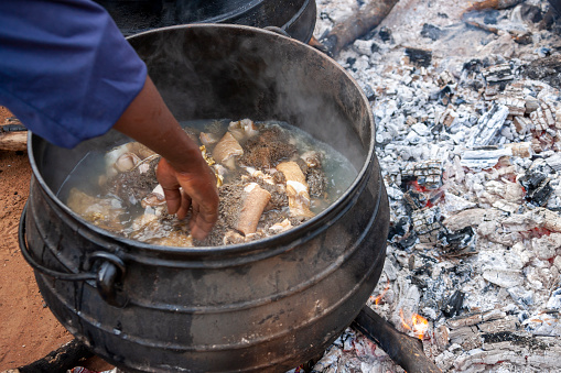 African man, cooking tripe in a big pots outdoors in the village, African kitchen in the backyard