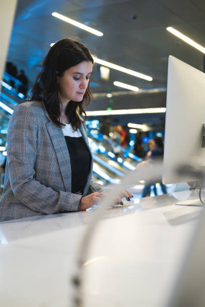 istock Female programmer or computer administrator working behind computer. Woman behind a desk with several computers and screens, repairing and installing new hardware 1210716262