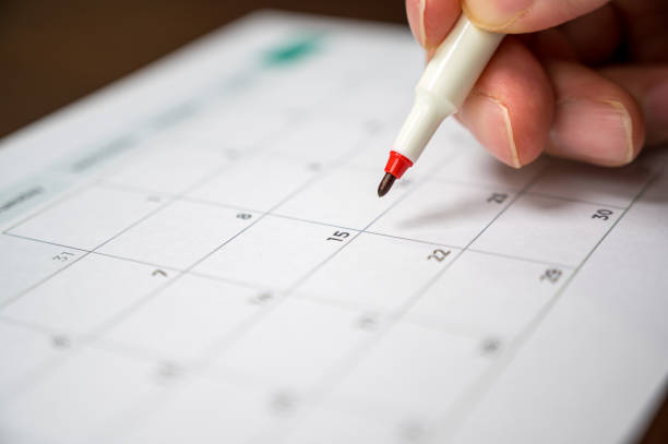 istock recording his schedule on a desktop calendar. 1210717393