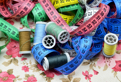 measuring tape and spools of thread on fabric background