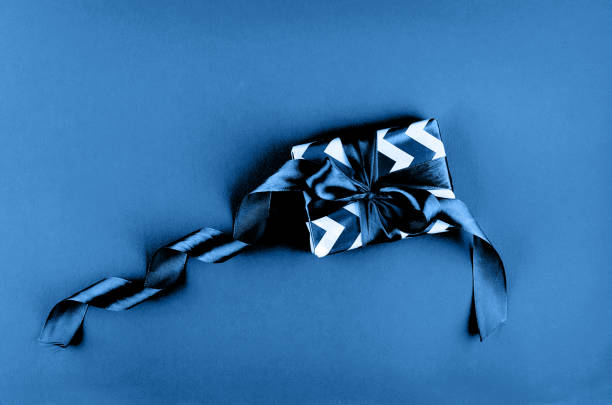 Blue goft box with striped ribbon and bow. Christmas box isolated on a white background. Closeup