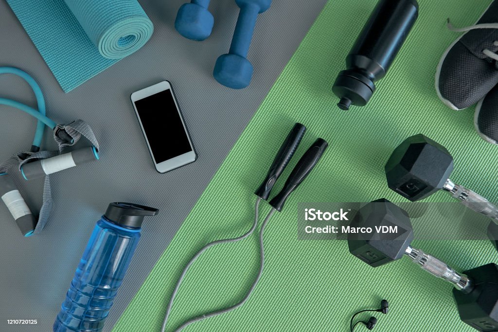 Choosing to live a healthy life High angle shot of a variety of workout equipment laid out on a green exercise mat before a workout Exercise Equipment Stock Photo
