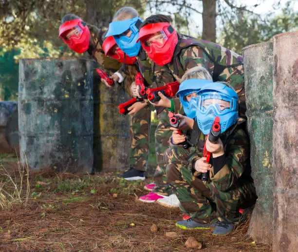 Photo of Kids paintball players aiming outdoors