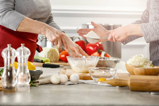 istock Chef`s hands working in the kitchen. Table background with kitchen tools and equipment and food products. Chef`s hands working in the kitchen. 1210724423