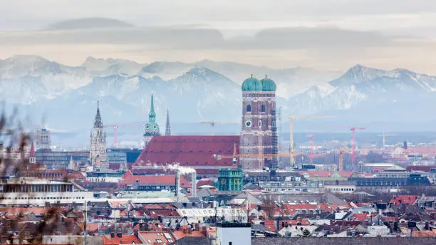 Frauenkirche with snow-capped alps in the background. Symbol & landmark of the bavarian capital. Beautiful panorama captured during winter season.