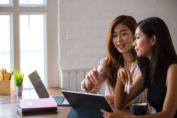 istock Two beautiful Asian students are using computers and textbooks. Review lesson at home With warm light 1210726938