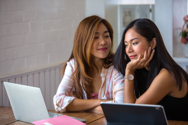 istock Two beautiful Asian students are using computers and textbooks. Review lesson at home With warm light 1210726939