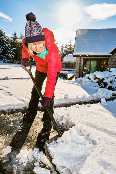 istock Senior woman clearing snow from her front yard using a snow shov 1210729037