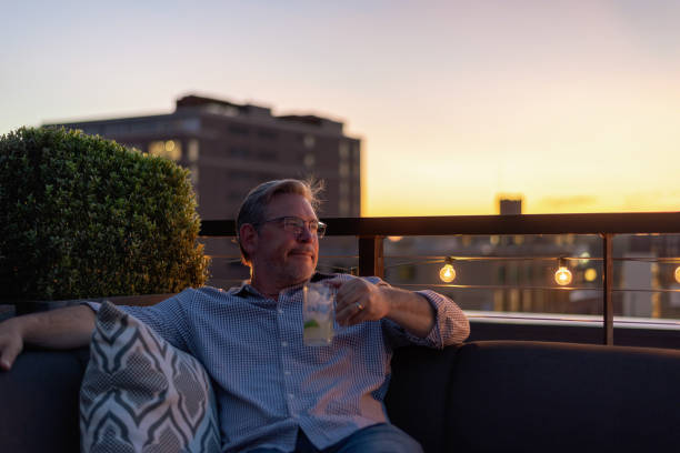 Man Looking Away While Sitting Against Sky During Sunset Photo taken in Minneapolis, United States golden hour drink stock pictures, royalty-free photos & images