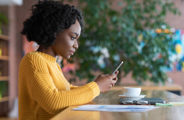 istock Concentrated black girl using smartphone at cafe 1210732140