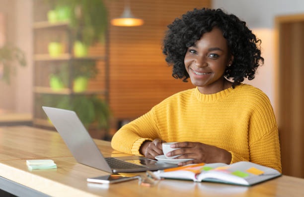 istock Smiling black woman having coffee break while looking for job 1210732379