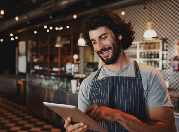 istock Cheerful young caucasian cafe owner wearing apron using digital tablet 1210732410