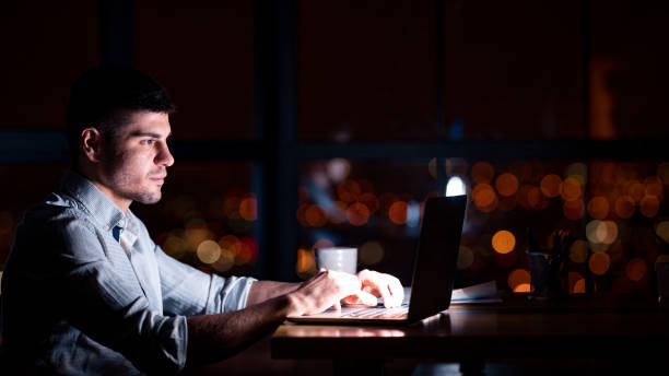 istock Young Businessman Working On Laptop Overtime In Modern Office, Panorama 1210733340