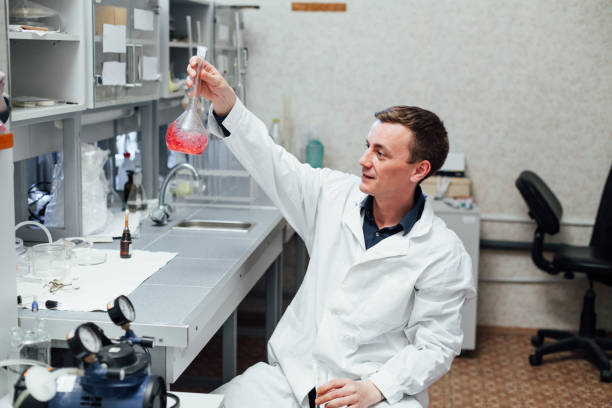 istock Investigator checking test tubes. Man wears protective goggles and mask 1210734996