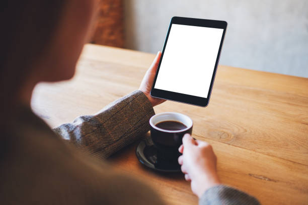 istock woman holding black tablet pc with blank white screen while drinking coffee 1210737972