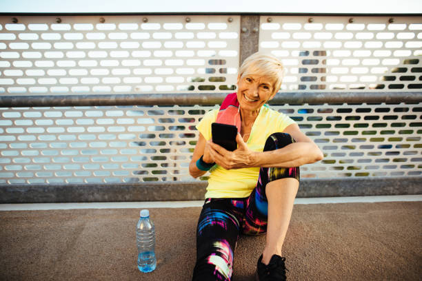 istock Senior woman using mobile phone while resting from jogging 1210738181