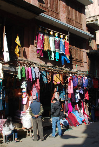 deux hommes s’accrochent devant leur boutique de mode à la rue commerçante de kathamandu. - nepal bazaar kathmandu textile photos et images de collection