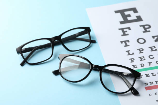 istock Glasses and eye test chart on blue background, close up 1210741039
