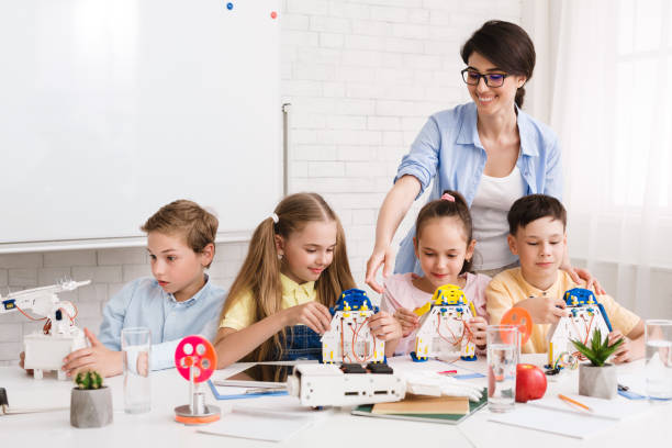 istock Robotics class at school. Kids creating robots with teacher 1210742491