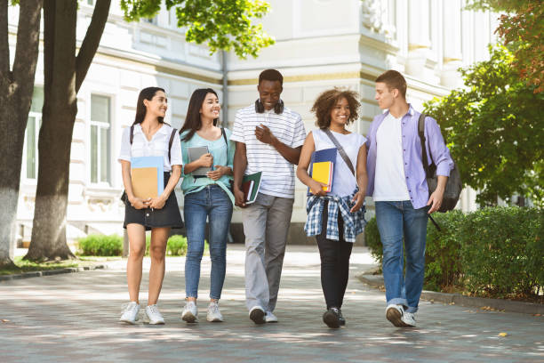 group of multiethnic students walking together outdoors in college campus - adult education full length book imagens e fotografias de stock