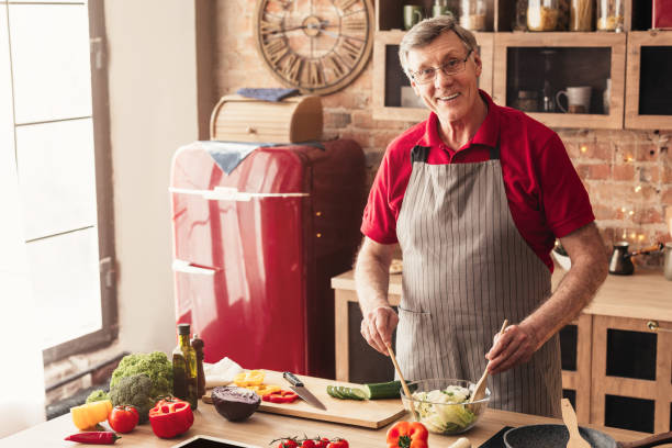istock Smiling Aged Man Preparing Fresh Vegetable Salad, Enjoying Cooking In Kitchen 1210745592