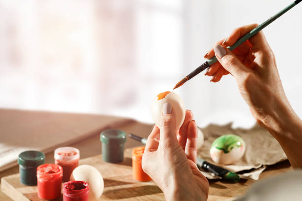 istock Female hands painting Easter eggs on wooden table on a spring day. Easter decoration time. 1210745806