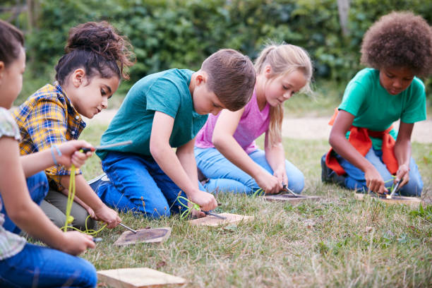 istock Group Of Children On Outdoor Camping Trip Learning How To Make Fire 1210747710