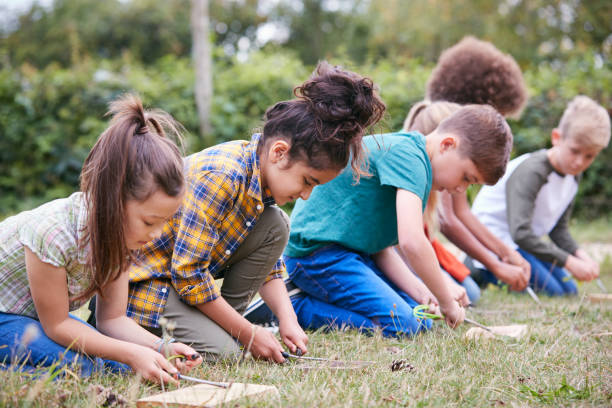 istock Group Of Children On Outdoor Camping Trip Learning How To Make Fire 1210747744