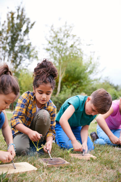 istock Group Of Children On Outdoor Camping Trip Learning How To Make Fire 1210748331