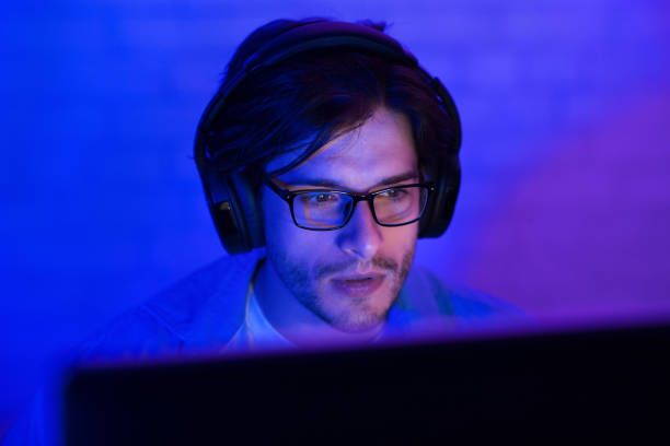 istock Man In Headphones Working On PC Computer Indoor At Night 1210748520