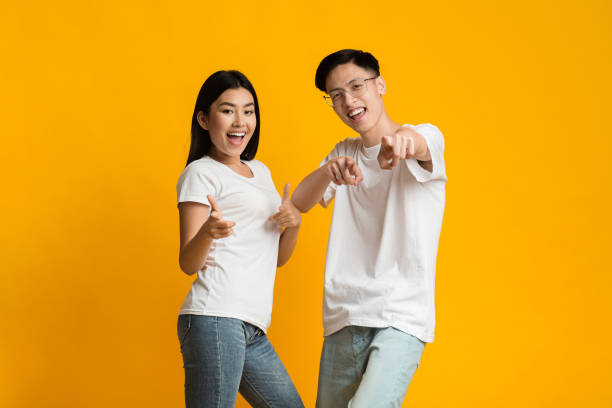 istock Happy asian couple having fun over yellow background 1210749072