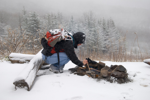 A hiker starts a fire in falling snow