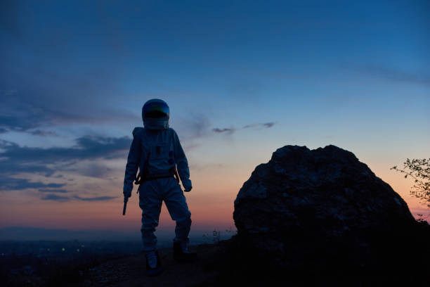 istock Astronaut standing on rocky hill during sunset. 1210750171