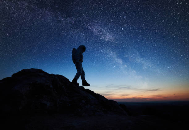 istock Space traveler walking down the rocky hill under starry sky. 1210750195